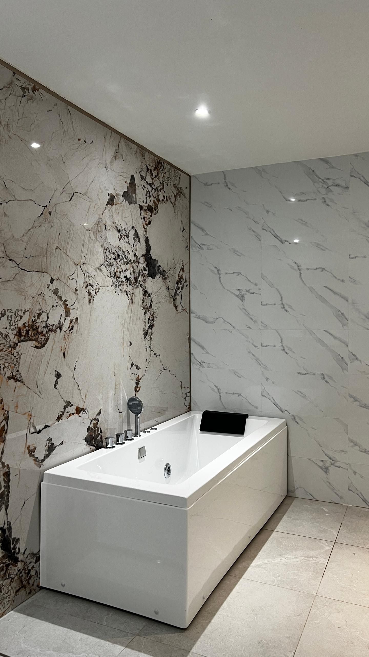 Un baño moderno con una bañera grande, paredes de mármol y un diseño minimalista.