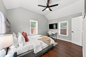 A bedroom with a bed, a desk, a television, and a ceiling fan. - Craftsman Bungalow in D'heart of the Arts District (Houston)