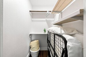 Une petite pièce, de taille modeste, avec des lits superposés, un panier à linge et une étagère sur laquelle se trouve un appareil électroménager vert.