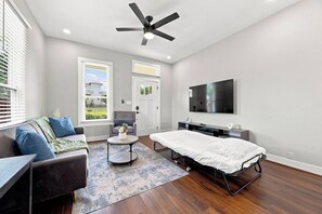 Une chambre moderne équipée d’un lit, d’un bureau, d’une chaise, d’un téléviseur et d’un ventilateur de plafond.
