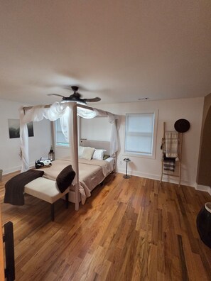 A bedroom with a four-poster canopy bed, a bedside table, a chair, a standing lamp, and a window with blinds. - Home away from home. Cozy. Comfortable. Clean (Atlanta)