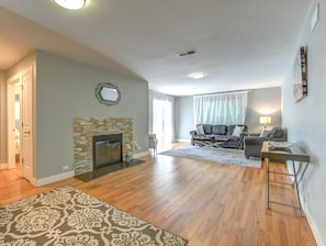 Ein Wohnzimmer mit Kamin, einer Sofagarnitur, einem Couchtisch und einem gemusterten Teppich.