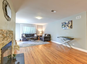 Ein Wohnzimmer mit Kamin, zwei Sofas, einem Couchtisch und einem Gemälde an der Wand.