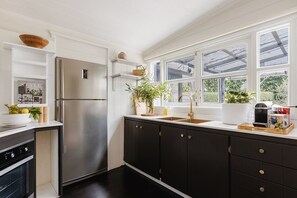 Eine moderne Küche mit einem Edelstahlkühlschrank, dunklen Schränken und einem Fenster mit Blick auf Grünflächen.