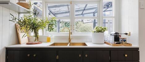 A kitchen with a large window, dark cabinets, and a white countertop.