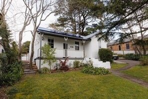 Ein eingeschossiges Haus mit Veranda, kleinem Garten und Auffahrt.