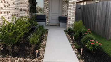 A residential house with a brick exterior, a front porch, and a pathway leading to the door.