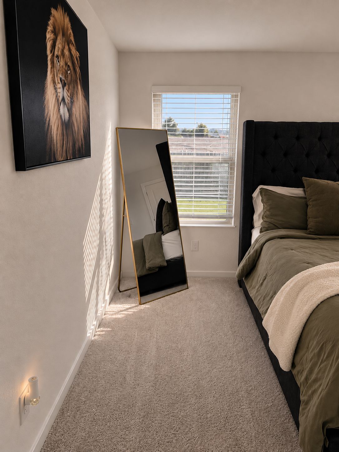 A bedroom with a bed, a large mirror, a painting of a lion, and a window with blinds.