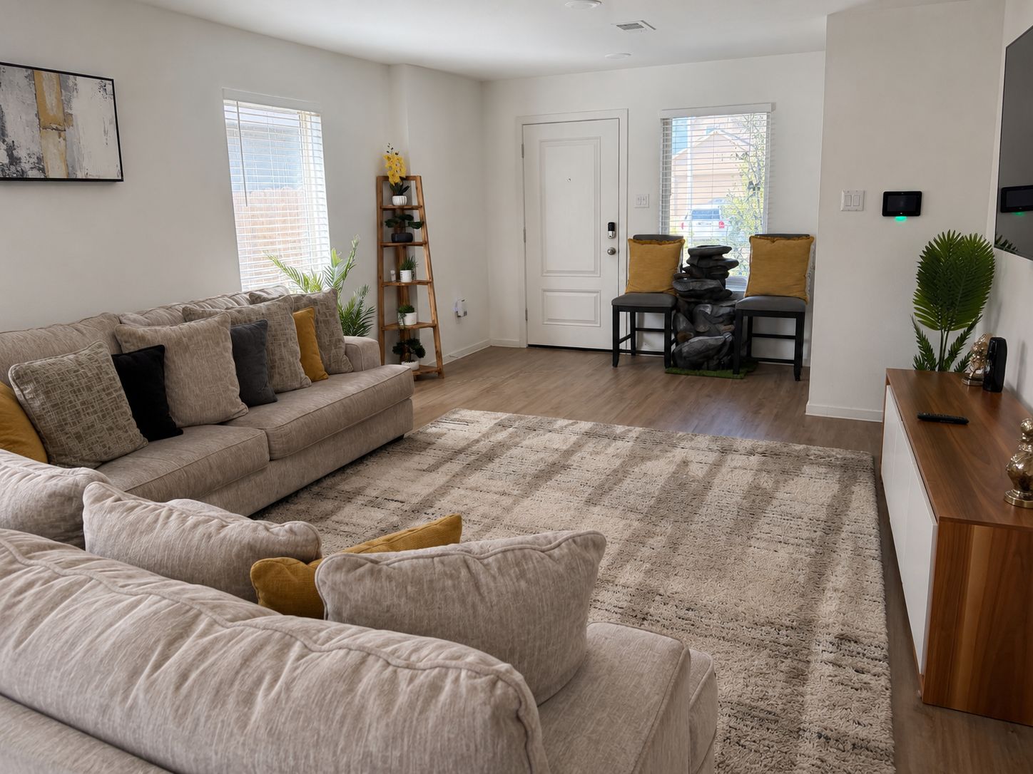 Ett vardagsrum med en soffa, ett soffbord och en matta. Det finns en dörr och ett fönster med persienner.