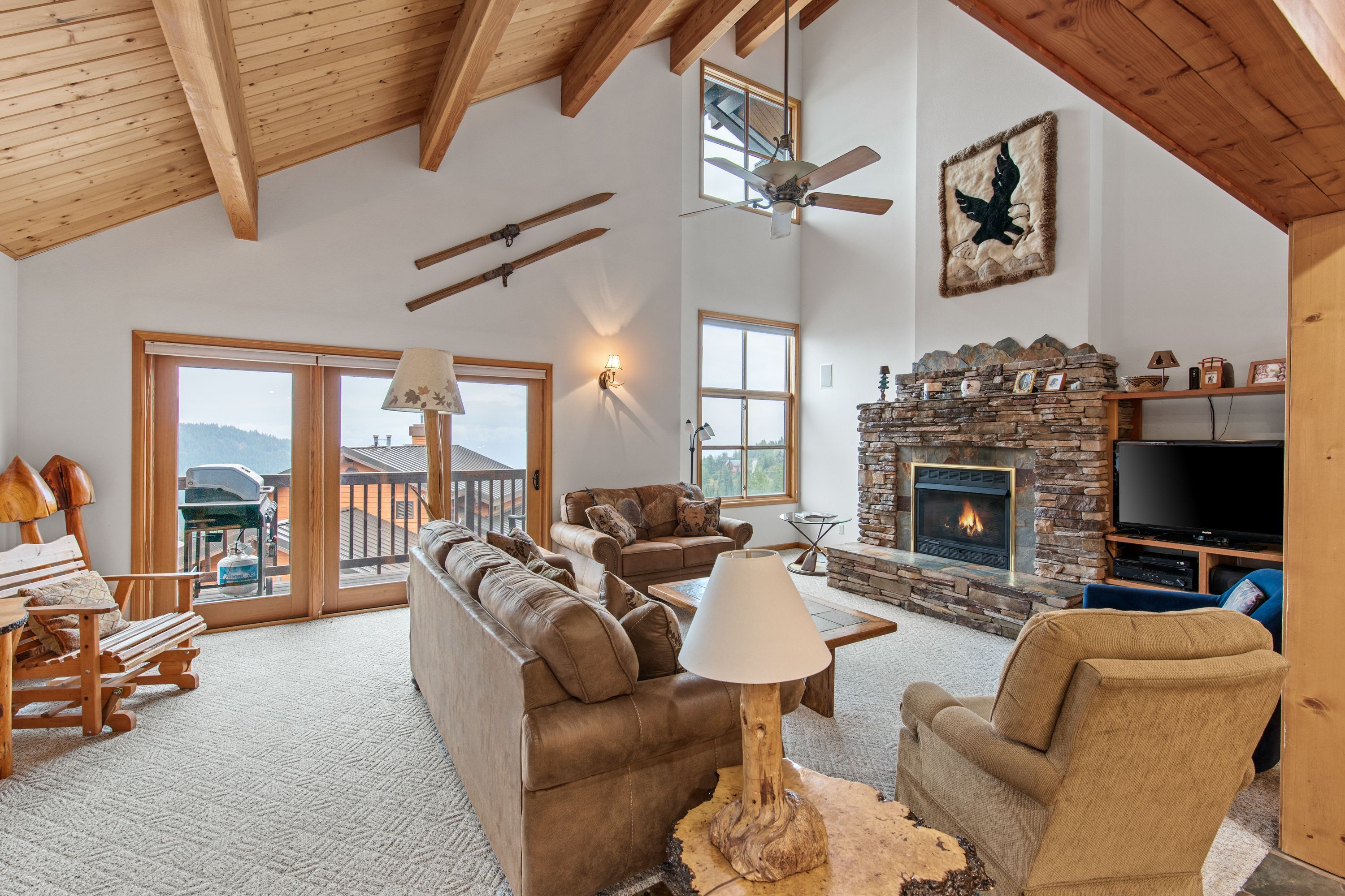 A spacious living room with a stone fireplace, leather sofas, and a television.