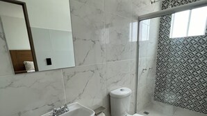 Et badeværelse med vask, toilet og bruser i marmor.
