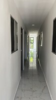 Un pasillo largo y estrecho con piso de baldosas brillantes y varias ventanas a cada lado.