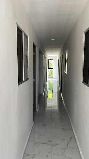 A long, narrow hallway with a glossy tiled floor and multiple windows on either side.