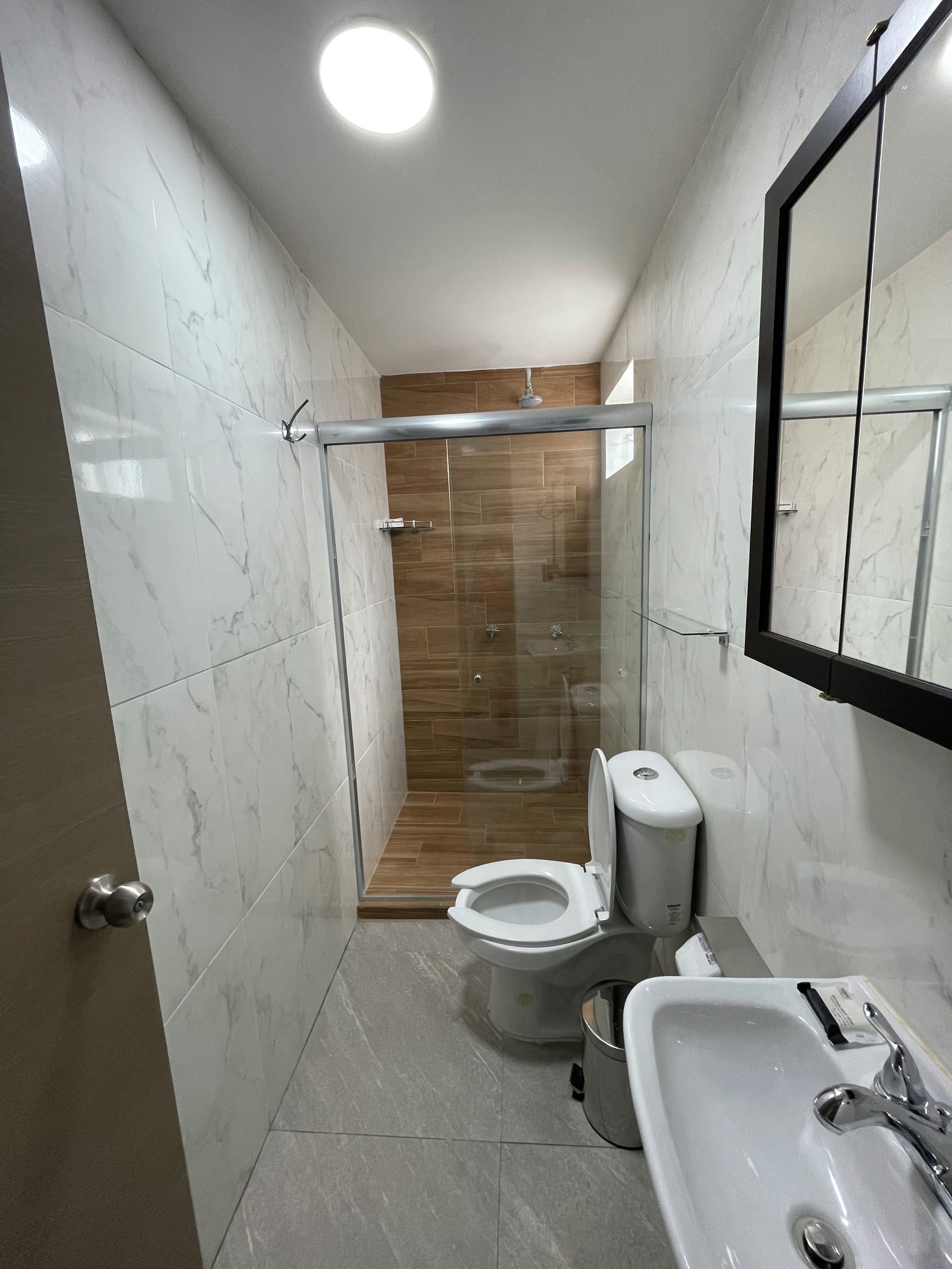 Uma casa de banho moderna com cabine de duche em vidro, sanita e lavatório.