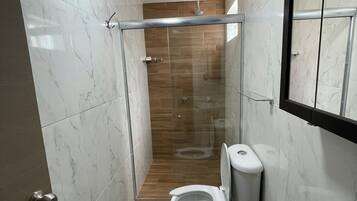 Uma casa de banho moderna com cabine de duche em vidro, sanita e lavatório.