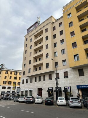 Ein mehrstöckiges Hotel mit schlichter Fassade, mehreren Balkonen und einem Eingangsbereich im Erdgeschoss.