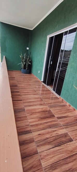 Une pièce avec un plancher en bois, des murs verts et une plante en pot.