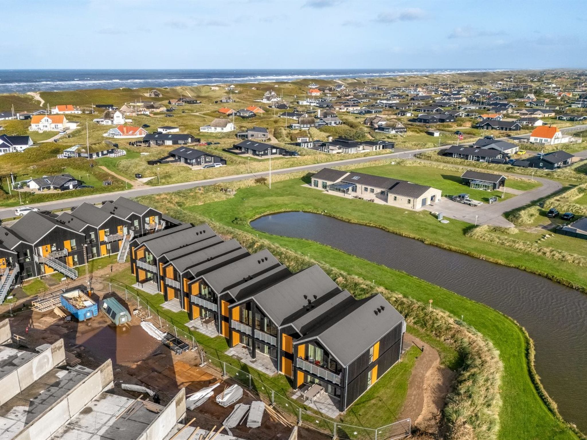 A residential area with modern houses, a river, and a clear view of the ocean.