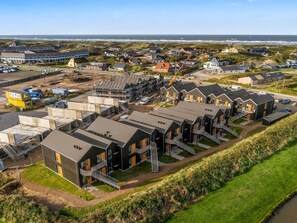 Una zona residencial costera con casas modernas, un sitio de construcción y vista al mar.