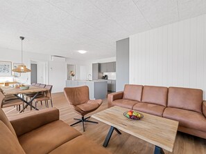 Una sala de estar moderna con un sofá, sillones y una mesa de centro.