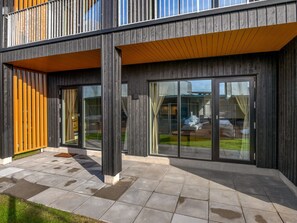 A modern building with large glass windows, a wooden deck, and a concrete patio. - "Fita" - 450m from the sea by Interhome (Ringkøbing)
