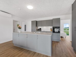 A modern kitchen with grey cabinets, a central island, and a view of the outdoors. - "Fita" - 450m from the sea by Interhome (Ringkøbing)