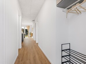 A narrow hallway with wooden flooring, white walls, and a black metal rack. - "Fita" - 450m from the sea by Interhome (Ringkøbing)