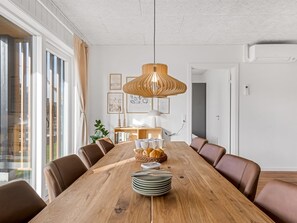 A dining area with a long wooden table, brown leather chairs, a hanging pendant light, and framed artwork on the wall. - "Fita" - 450m from the sea by Interhome (Ringkøbing)
