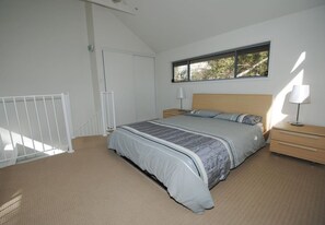 Une chambre à coucher avec un lit, des tables de chevet, une fenêtre et une porte.