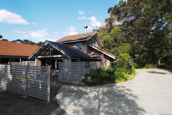 A residential property with a gated entrance, a sloped roof, and a driveway leading to the house.