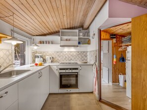 A modern kitchen with white cabinetry, a built-in oven, and a wooden ceiling. - "Kierulf" - 1km to the fjord by Interhome (Hemmet)