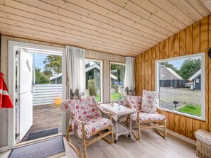 A room with wooden walls and ceiling, a dining table with chairs, and large windows offering views of the outside. - "Kierulf" - 1km to the fjord by Interhome (Hemmet)
