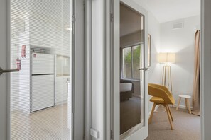 A hotel room with a bed, a chair, a lamp, and a view of the outside. - Sandy Bay Retreat with Marina Views – 2 Bedroom (Sandy Bay)