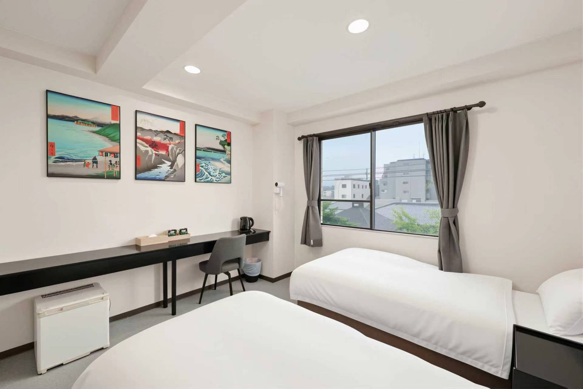 A hotel room with two beds, a desk, and a window with curtains.