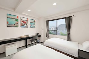 Habitación de hotel con dos camas, un escritorio y una ventana con cortinas.