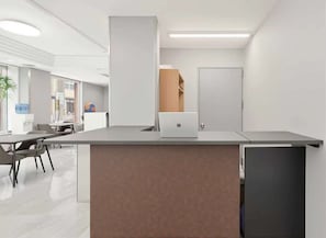 Un espace de bureau moderne avec un comptoir d’accueil, un ordinateur portable et une porte en arrière-plan.