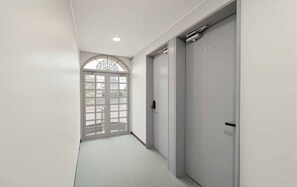 Un pasillo con una puerta marcada '406' y una puerta de cristal decorativa al final.