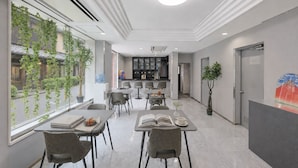 A modern hotel lobby with a dining area, a kitchen in the background, and a large window with greenery. - ATO Hotel Kyoto (Kyoto)
