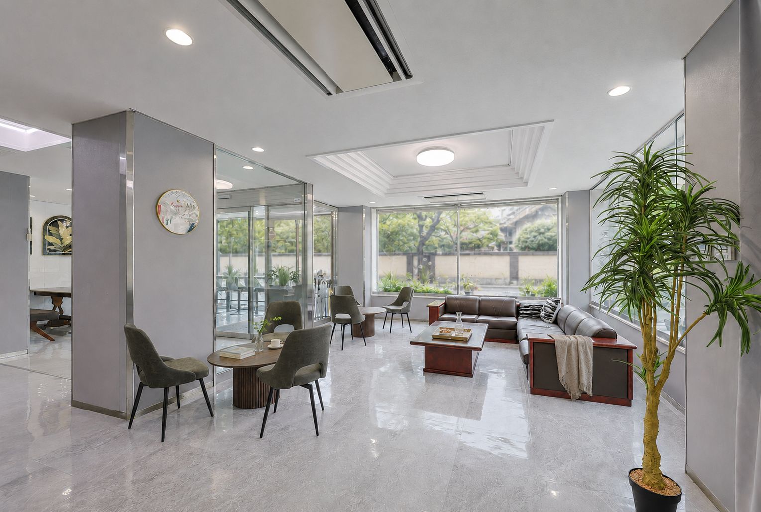 A modern interior with a seating area, a dining space, and large windows offering a view of the outdoors.