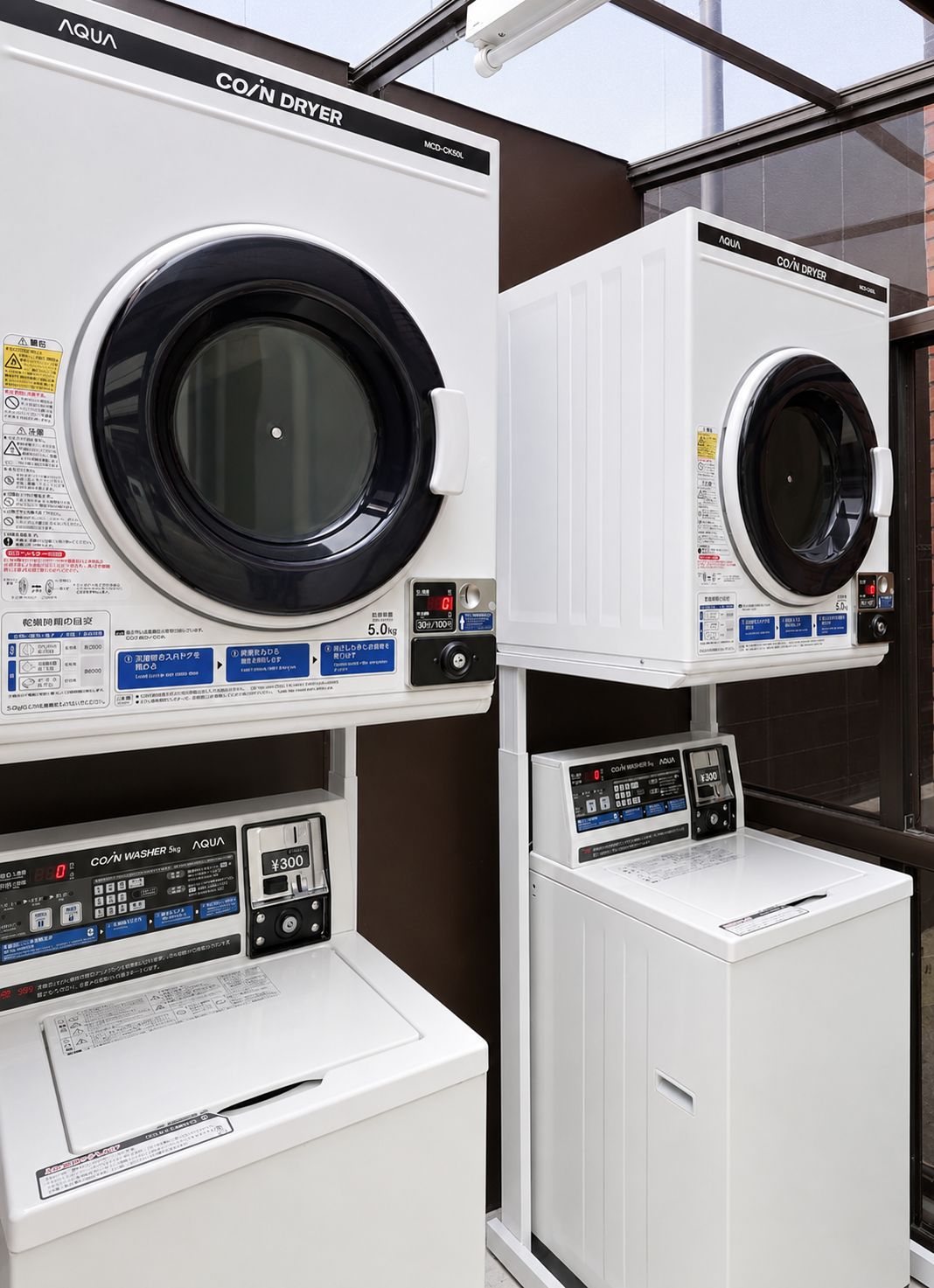 A laundry facility with two front-loading washing machines and a coin-operated dryer.