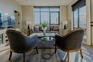 A modern living room with a sofa, two armchairs, a coffee table, and a TV. - Luxurious 2 bed 2 bath Corner Unit-City View #521 (Nashville)
