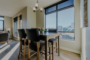 A dining area with a table, chairs, and a chandelier. There are windows with a city view. - Luxurious 2 bed 2 bath Corner Unit-City View #521 (Nashville)