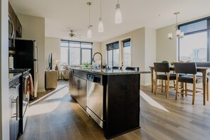 A modern kitchen with a central island, stainless steel appliances, and a dining area with a view. - Luxurious 2 bed 2 bath Corner Unit-City View #521 (Nashville)