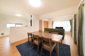 Una sala moderna con una mesa de comedor, sillas, un sofá y un televisor.