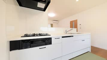 A modern kitchen with a gas stove, dishwasher, and a large mirror above the countertop.