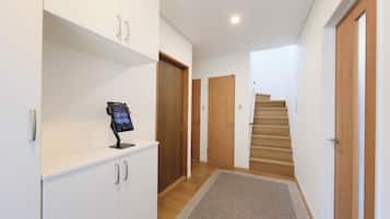 A hallway with a digital information kiosk, wooden doors, and a carpeted staircase.