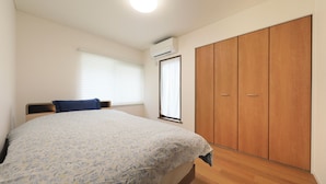 Ein Schlafzimmer mit Bett, Kleiderschrank und einem Fenster mit Jalousien.