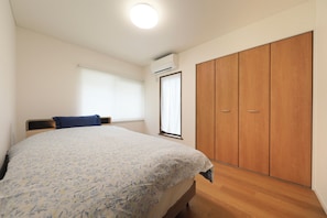 Un dormitorio con cama, armario y ventana con persianas.