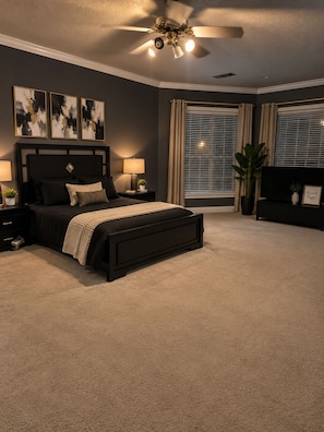 A bedroom with a bed, nightstands, a ceiling fan, a TV, and a window with blinds. - Spacious 6-bedroom house with AC in superb De Kalb (De Kalb)