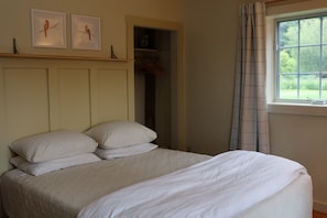 A bedroom with a bed, pillows, a window with curtains, and two wall-mounted bird paintings.